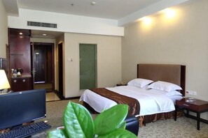 A hotel room with a bed, bedside table, lamp, TV, and a plant. - Hua'an Hotel (Hua'an)