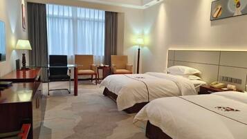 Habitación de hotel con dos camas, un escritorio, una silla, un televisor y una lámpara.