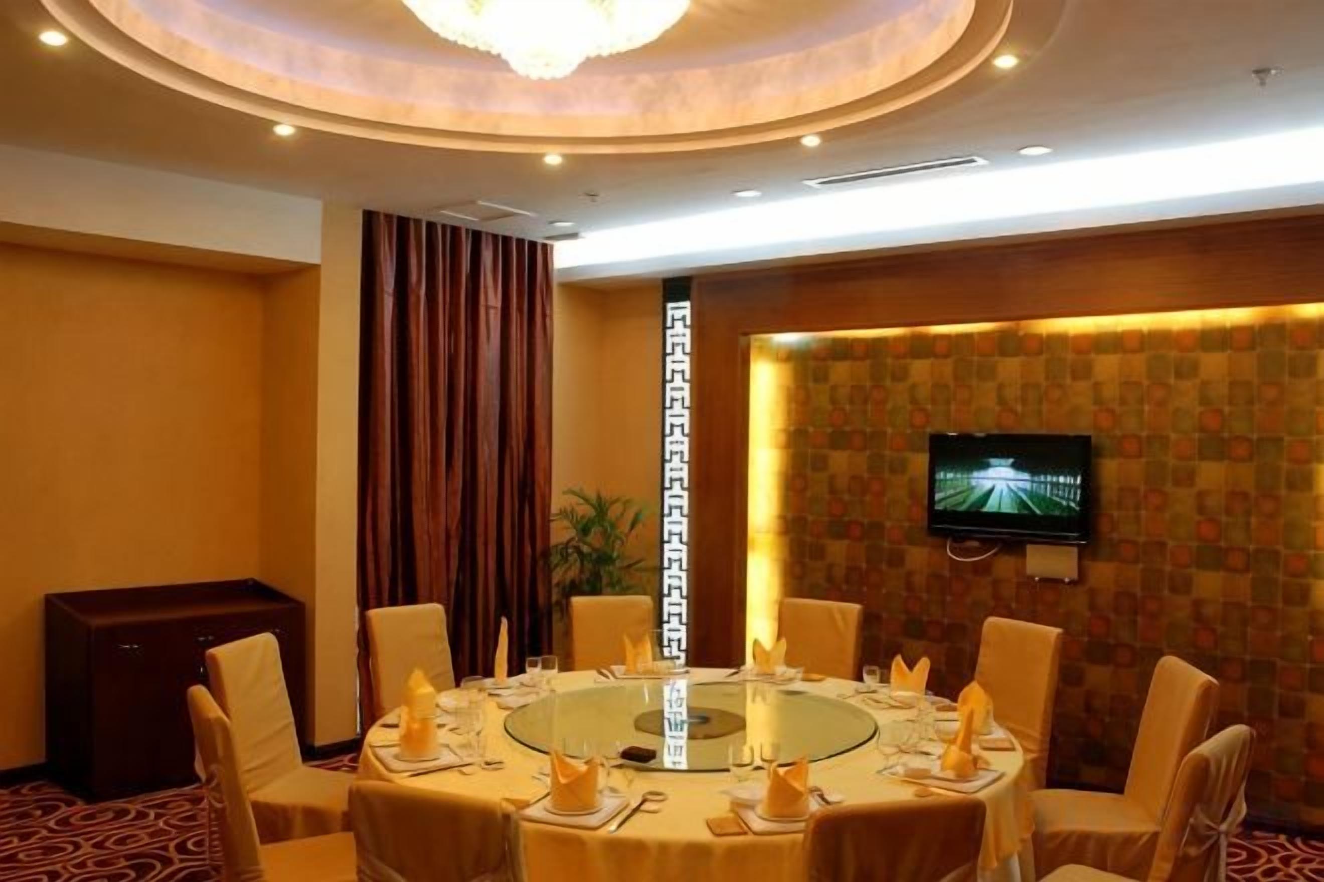A conference room with a round table, chairs, a television, and a decorative pillar.