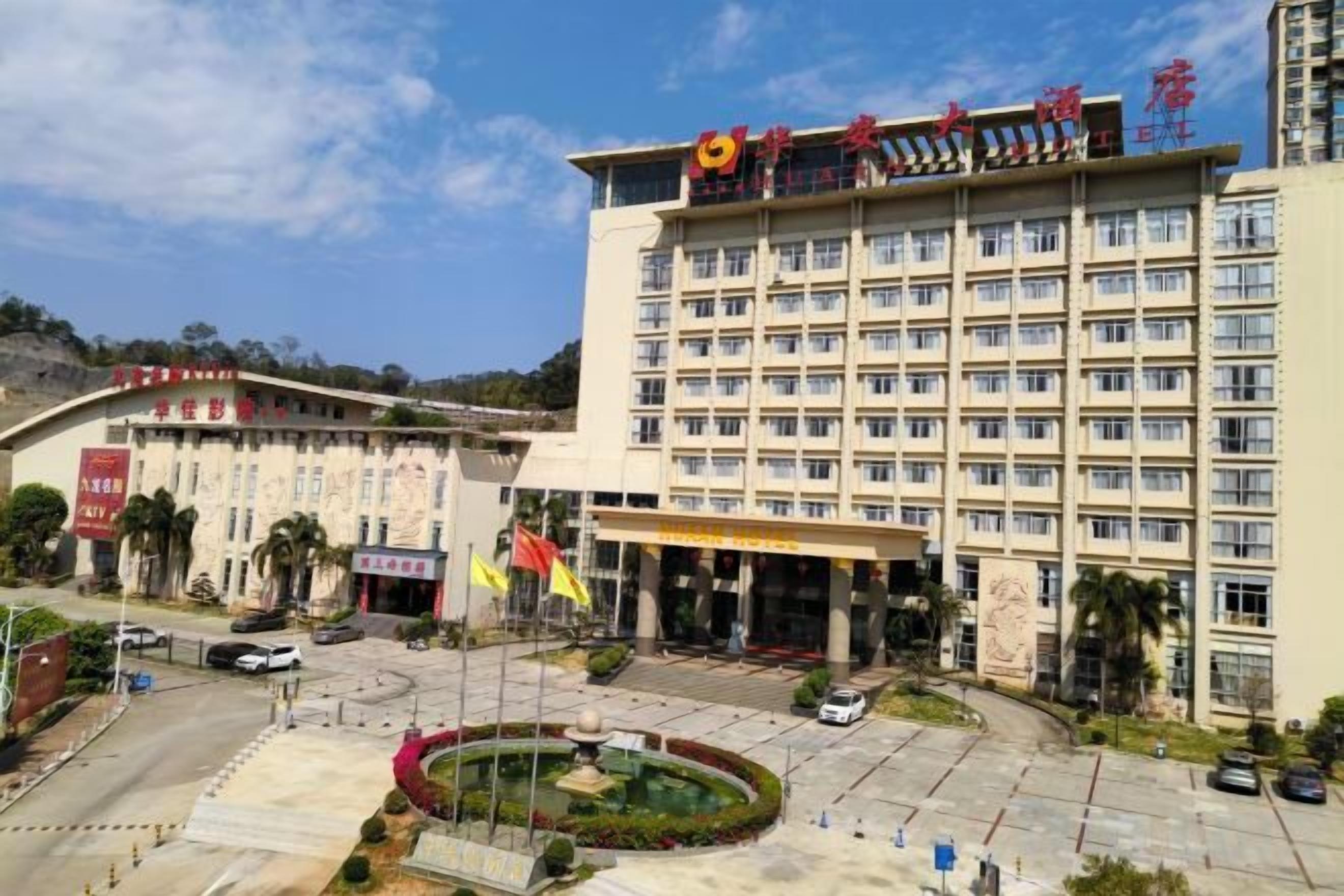 A multi-story hotel with a central courtyard, flagpoles, and a parking area.
