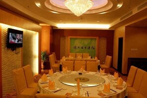 A conference room with a round table, chairs, a television, and a banner with Chinese characters. - Hua'an Hotel (Hua'an)