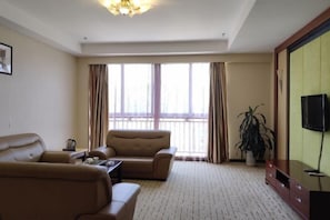 A hotel room with a sofa, a television, a large window with curtains, and a potted plant. - Hua'an Hotel (Hua'an)
