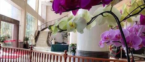 A hotel lobby with a staircase, a railing, and potted plants.