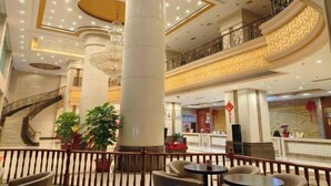 A hotel lobby with a grand staircase, large columns, and a reception desk. - Hua'an Hotel (Hua'an)