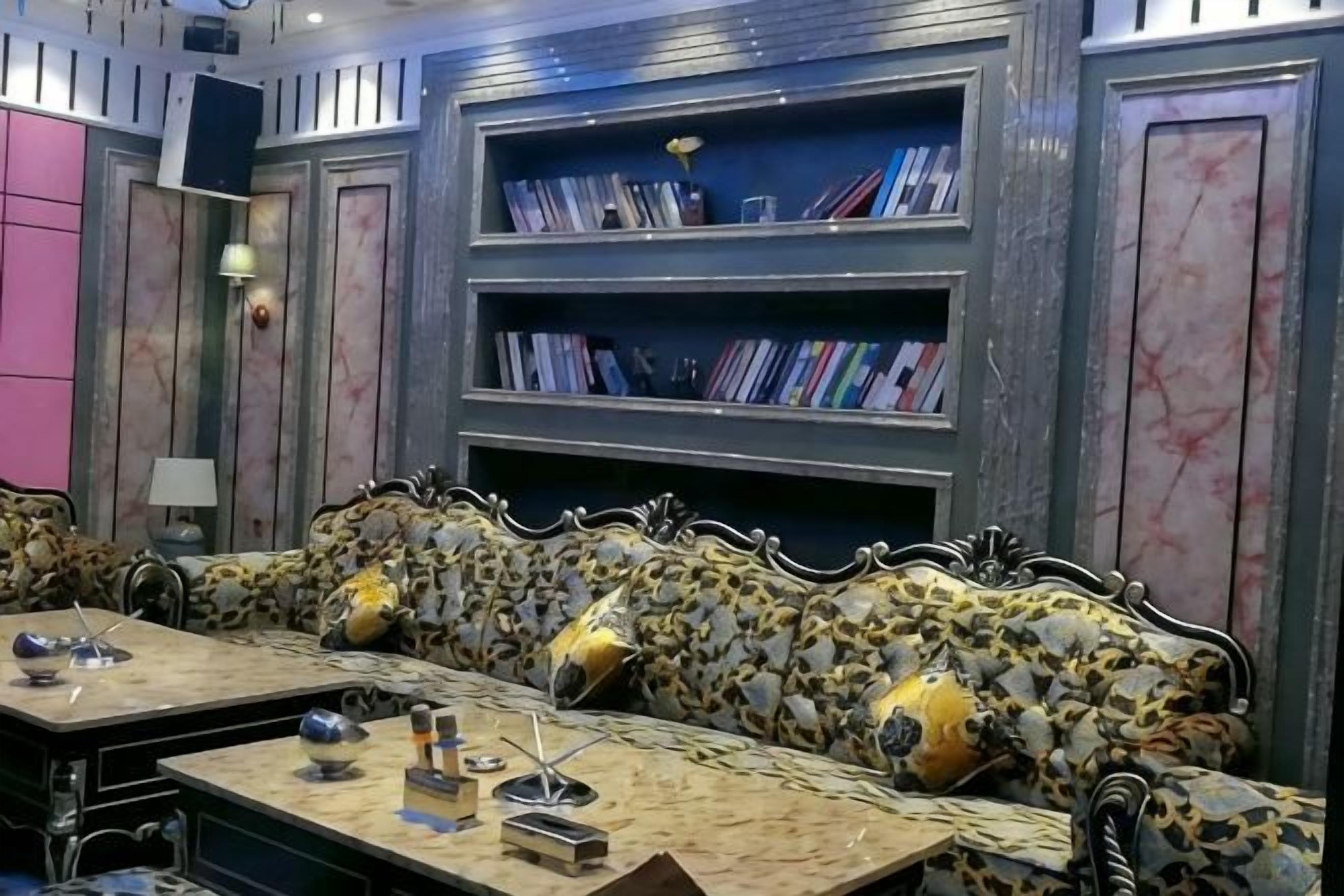 A room with a sofa and a table, a bookshelf, and a lamp.