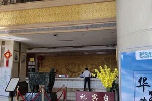 A reception area with a marble counter, a receptionist, and a sign with Chinese characters. - Hua'an Hotel (Hua'an)