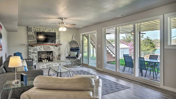 A spacious living room with a stone fireplace, comfortable seating, and large sliding glass doors leading to an outdoor patio.