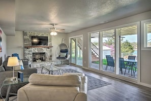 A spacious living room with a stone fireplace, comfortable seating, and large sliding glass doors leading to an outdoor patio.