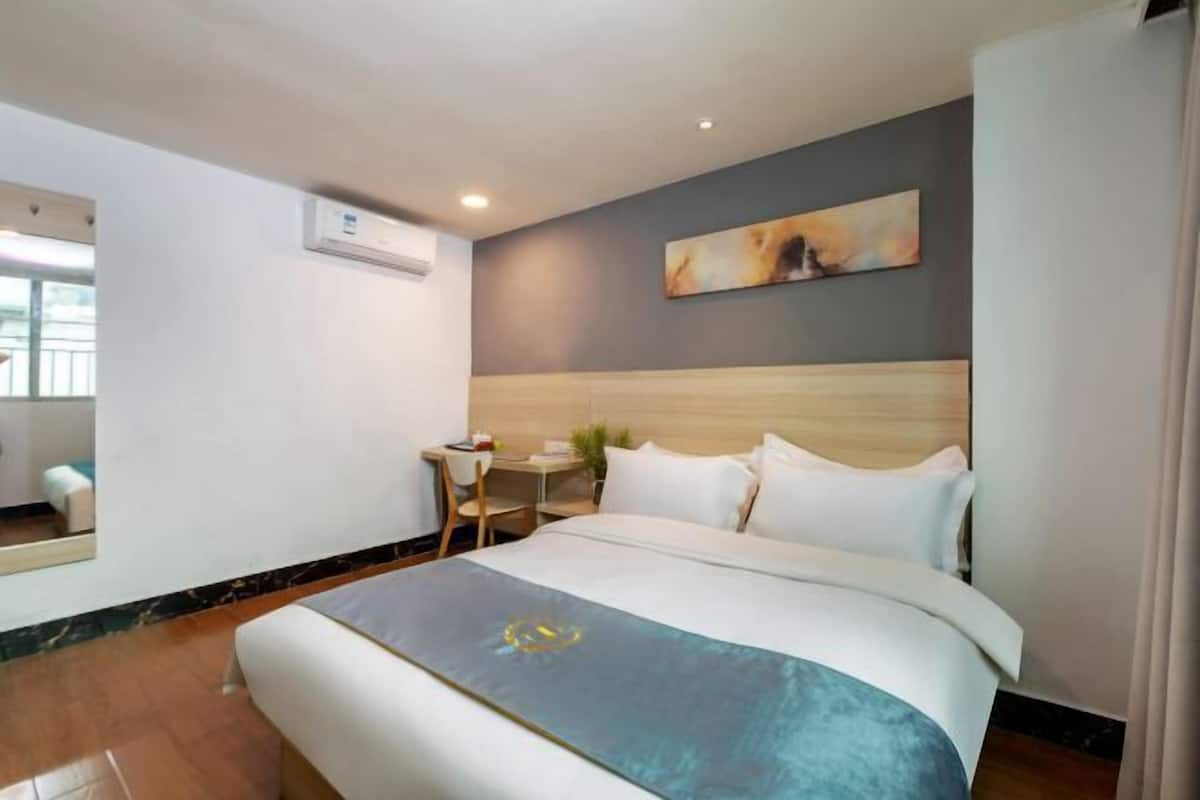 Ein Hotelzimmer mit Bett, Schreibtisch, Stuhl, Spiegel und einem Bild an der Wand.