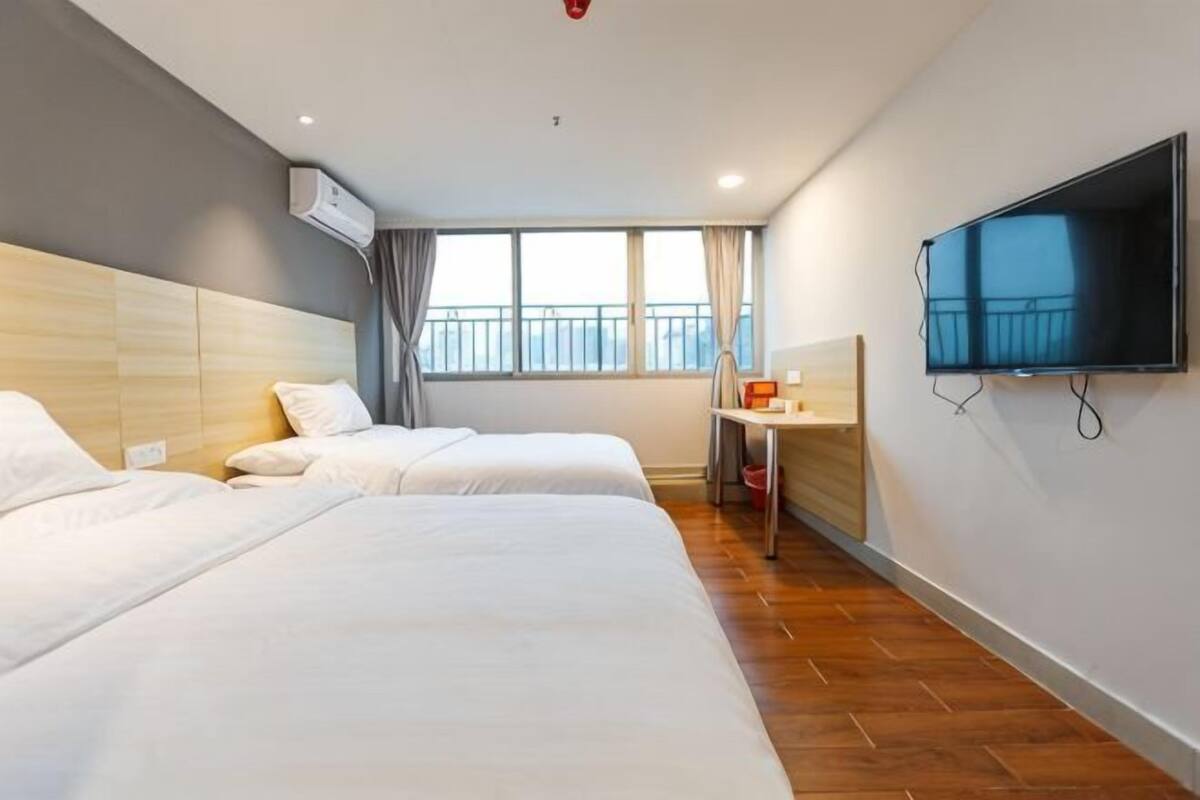 Ein Hotelzimmer mit zwei Betten, einem Fernseher, einem Schreibtisch und einem Fenster mit Blick.