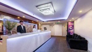 A hotel reception area with a reception desk, a black sofa, a potted plant, and a chandelier. - Shenzhen Lanyu Hotel (Dongmen Old Street) (Shenzhen)
