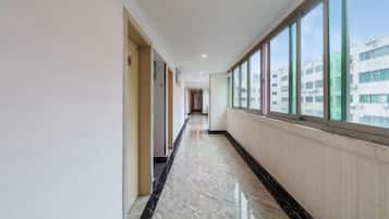 A corridor with a marble floor, large windows, and a view of buildings outside.