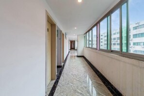 A corridor with a marble floor, large windows, and a view of buildings outside. - Shenzhen Lanyu Hotel (Dongmen Old Street) (Shenzhen)