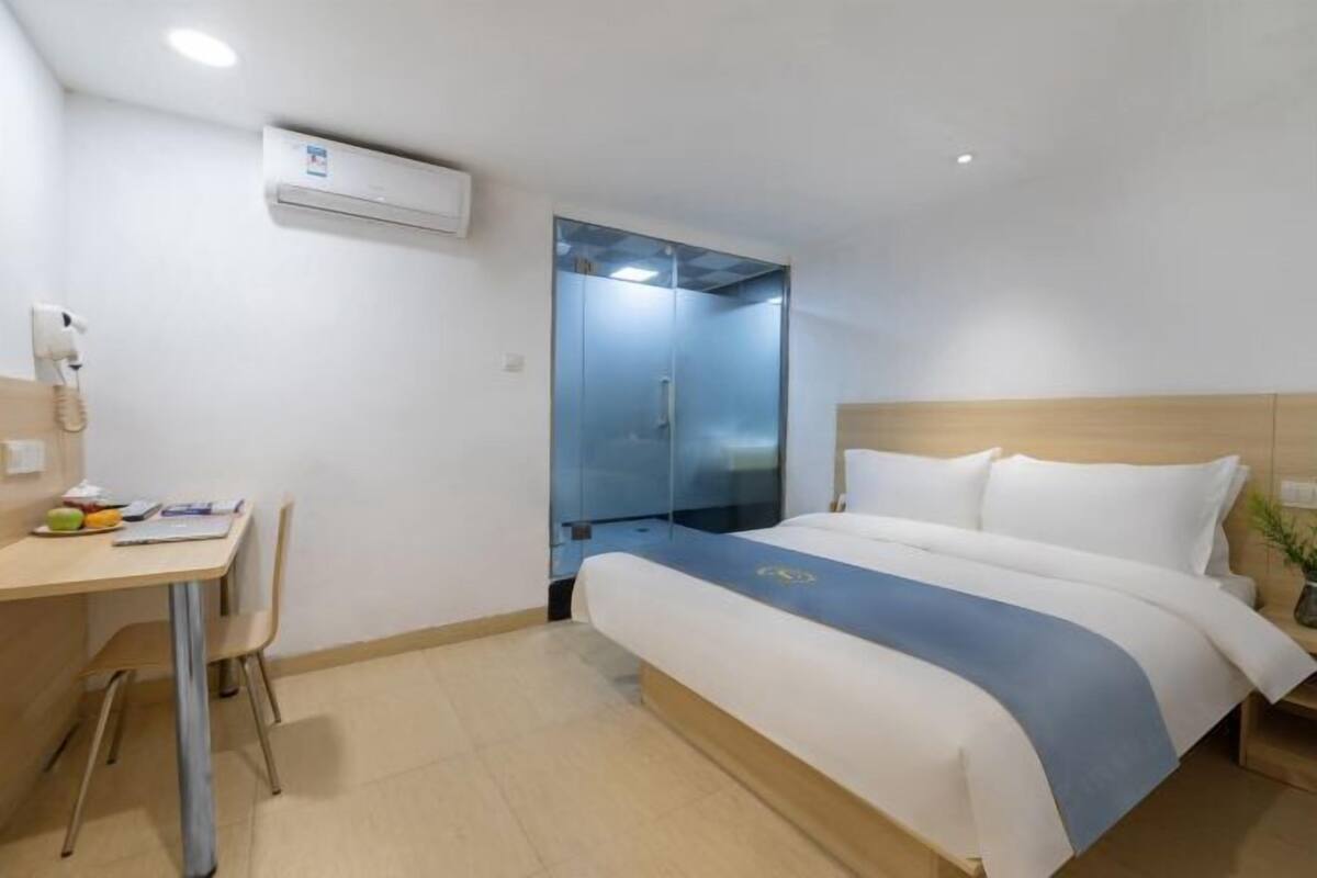 Ein Hotelzimmer mit Bett, Schreibtisch mit Stuhl, Klimaanlage und Spiegel.