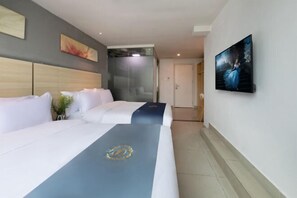 Ein Hotelzimmer mit zwei Betten, einem großen Gemälde an der Wand und einer Glastrennwand.