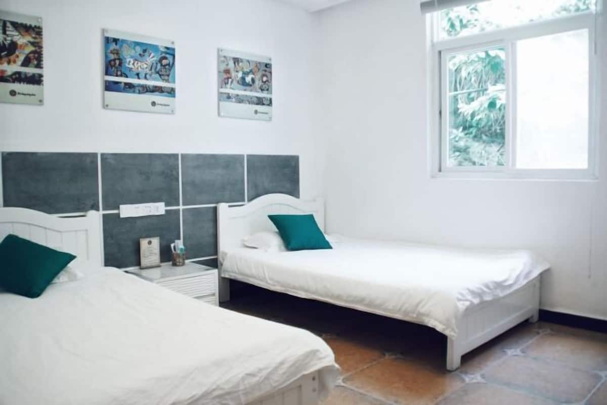 Habitación con dos camas, una ventana y decoración en las paredes.