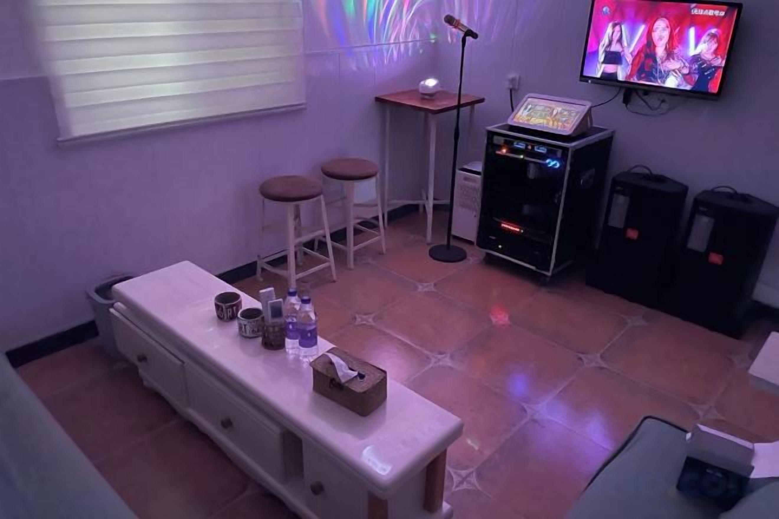 A room with a bar area, stools, a television, and a sound system.