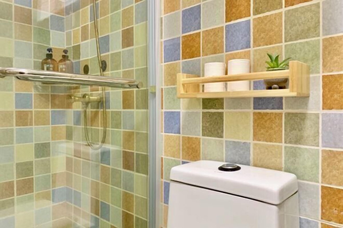 Une salle de bain avec une douche à parois de verre, des toilettes et une étagère contenant des articles de toilette.