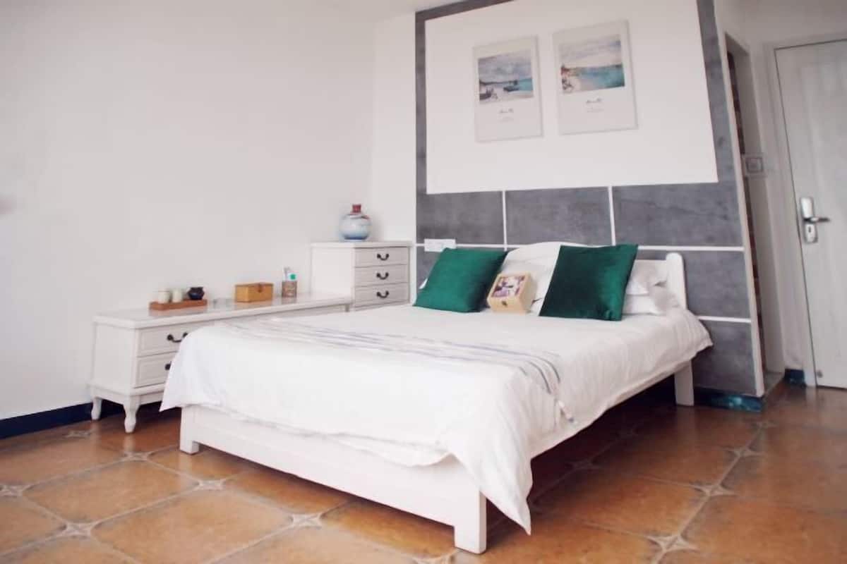 Un dormitorio con cama, cómoda blanca y dos cuadros en la pared.