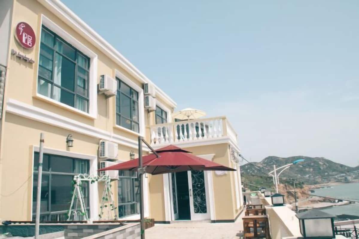Un hotel con balcón, mobiliario exterior y vistas al mar.