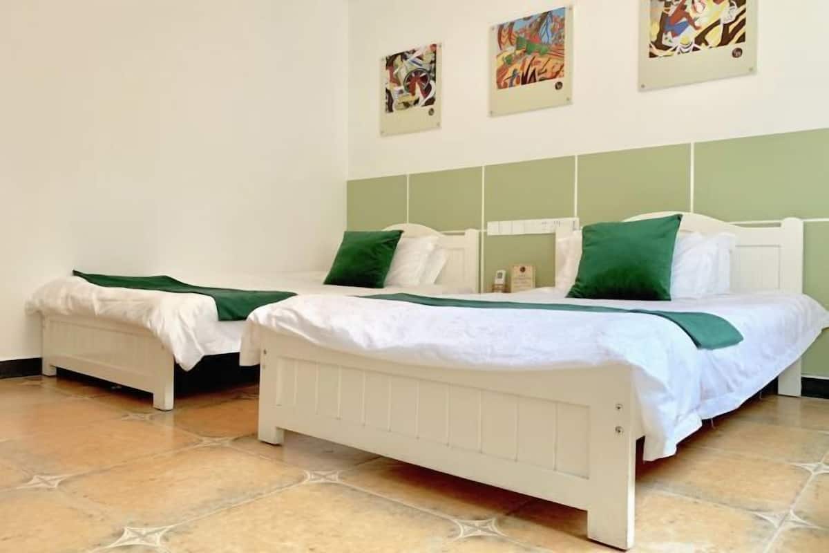 Una habitación con dos camas individuales, un radiador y obras de arte en la pared.