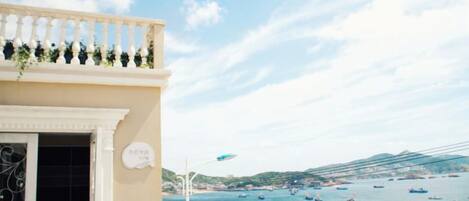 A coastal building with a balcony overlooking a bay with boats.