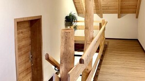A wooden staircase with a handrail, a wooden door, and a plant on the landing.