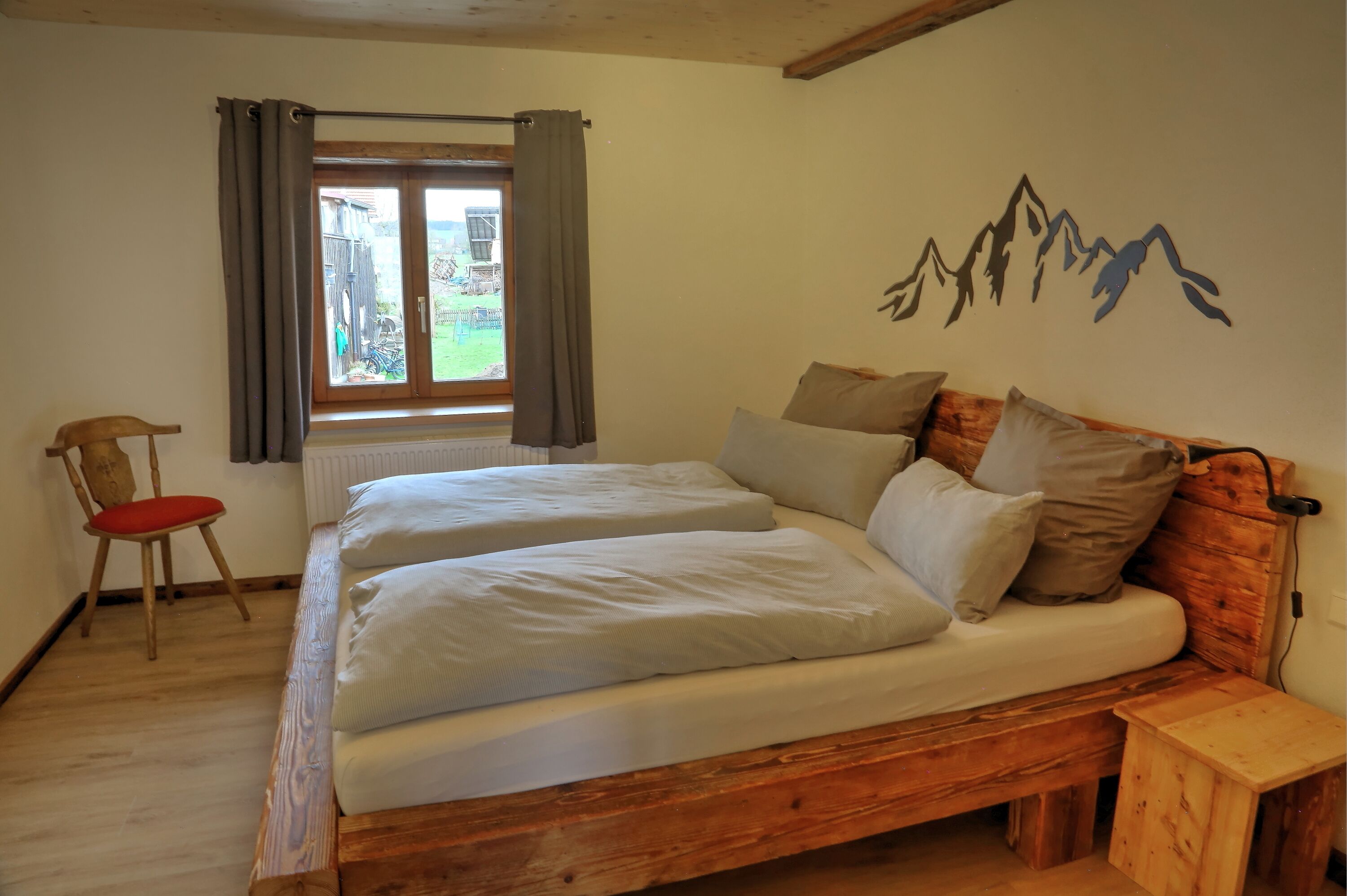 A double bed with white linens, a wooden headboard, and a small wooden nightstand.