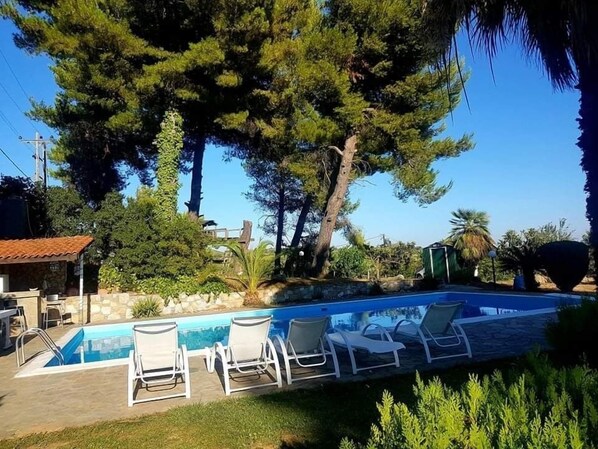 Une piscine avec des chaises longues et un mur en pierre.