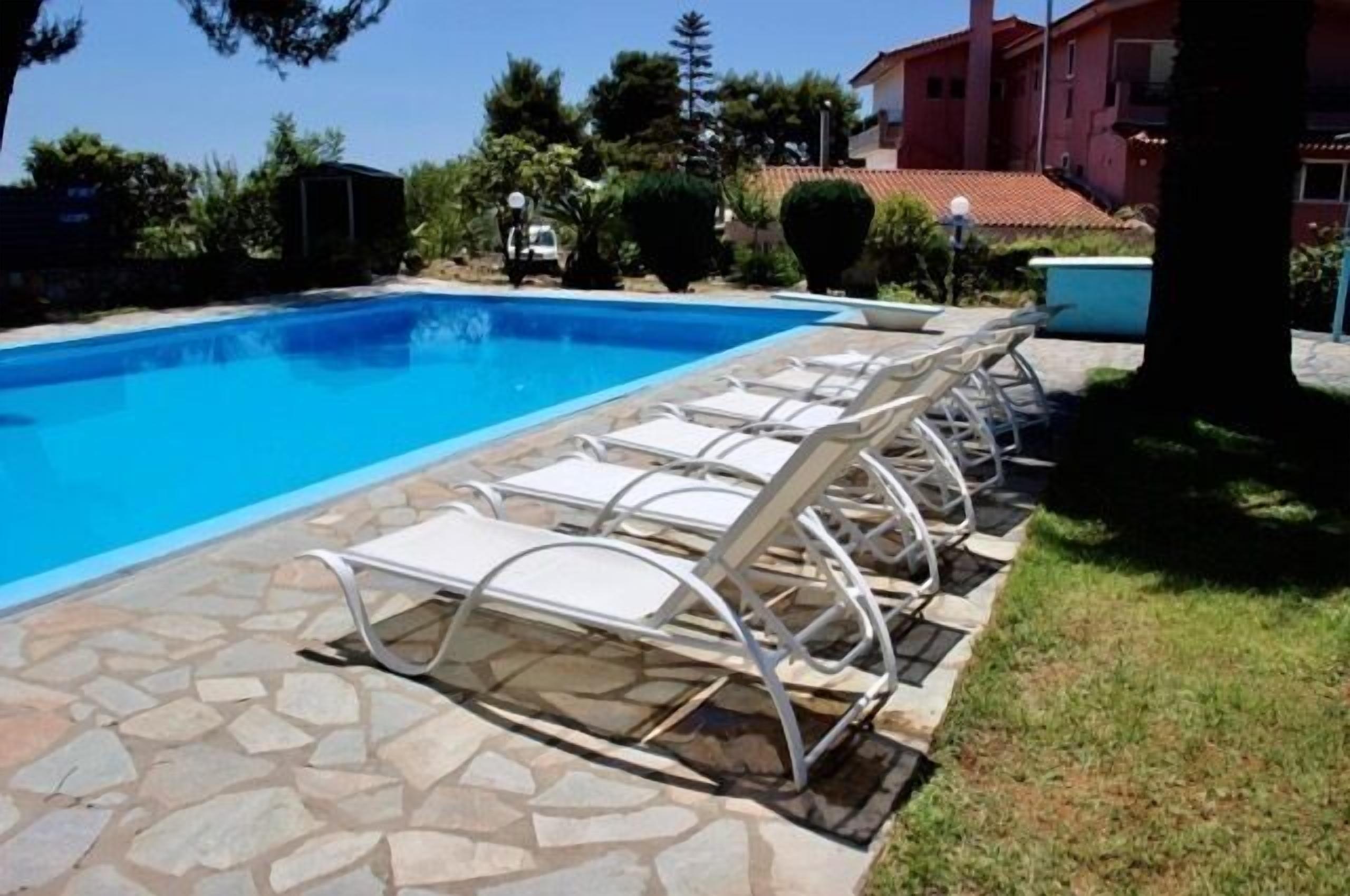 En swimmingpool med liggestole og en terrasse belagt med sten.