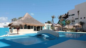 Ein Swimmingpool mit einer strohgedeckten Struktur, Palmen und einem Fitnessraum.