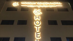 Een hotelschild met de naam 'Holiday Season Hotel' in het Engels en Arabisch.
