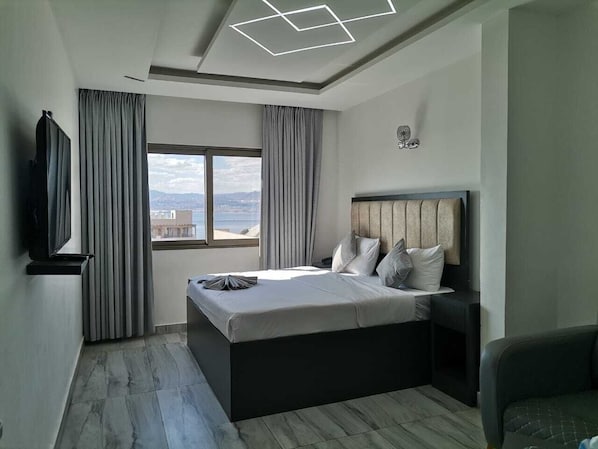 A modern bedroom with a bed, a TV, and a view of the city.