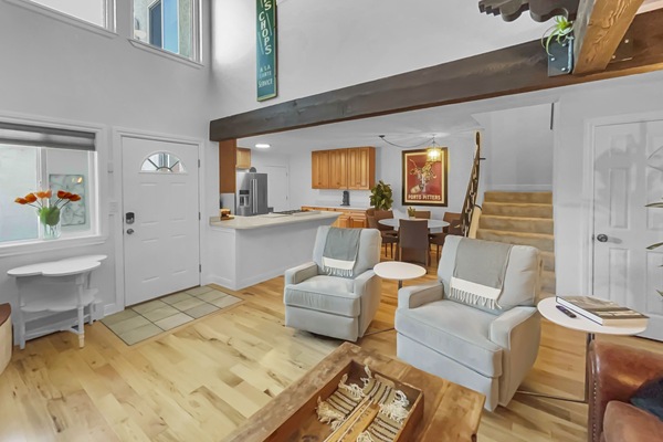 A cozy living space with two armchairs and a view into the kitchen area.