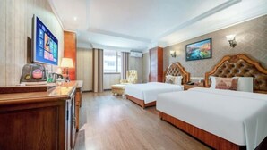 Habitación de hotel con dos camas, un escritorio con computadora, televisión y ventana con cortinas.