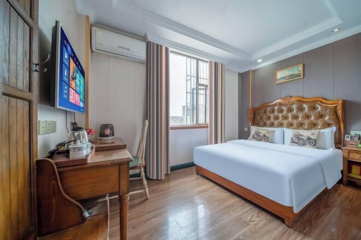 Een hotelkamer met een bed, een bureau, een stoel, een televisie en een raam.