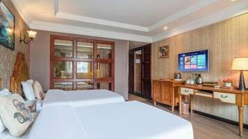A hotel room with two beds, a desk with a computer, a television, and a wooden wall panel.