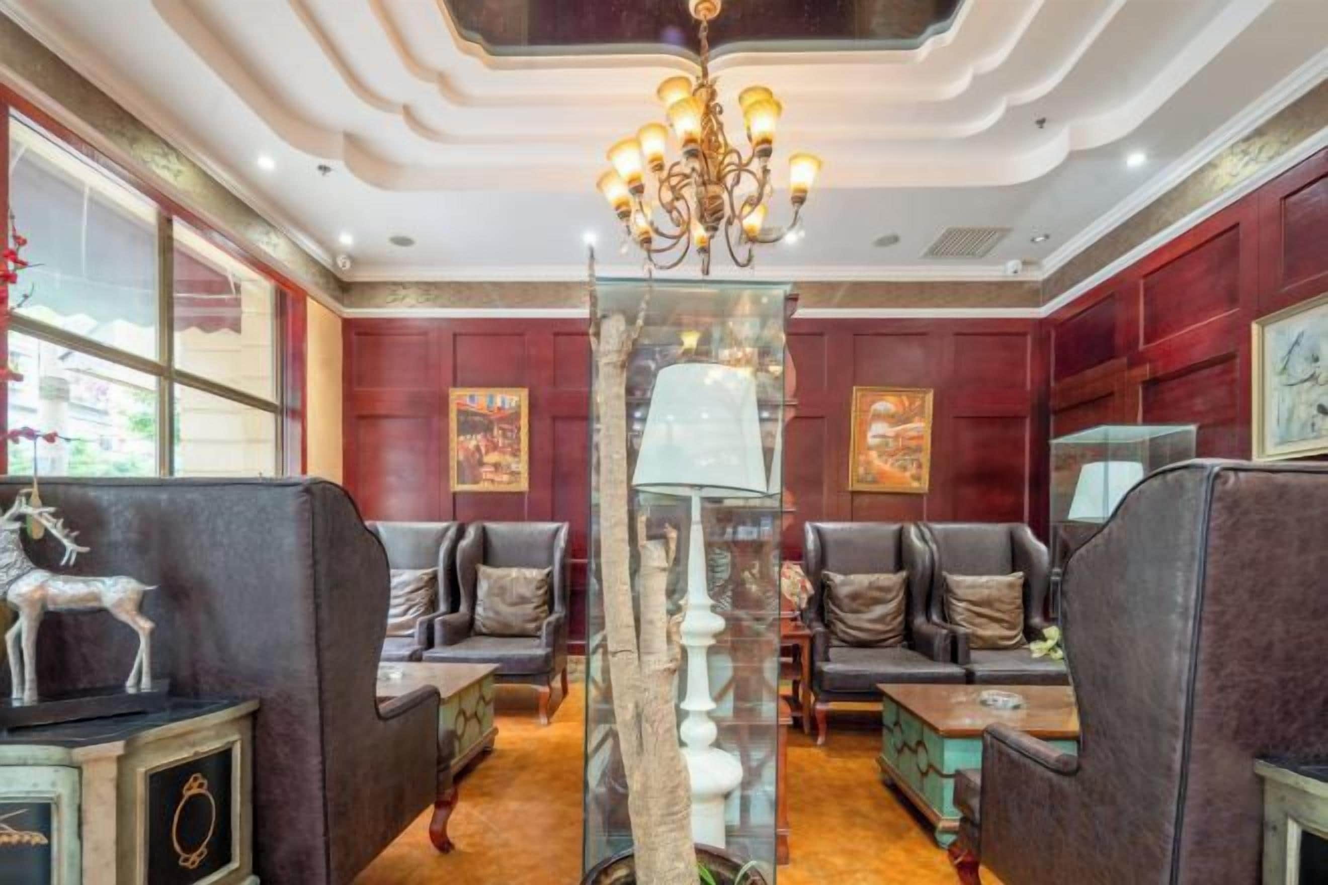 Um saguão de hotel com sofás de couro, um candelabro e um pilar de vidro decorativo.