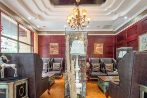 Um saguão de hotel com sofás de couro, um candelabro e um pilar de vidro decorativo.