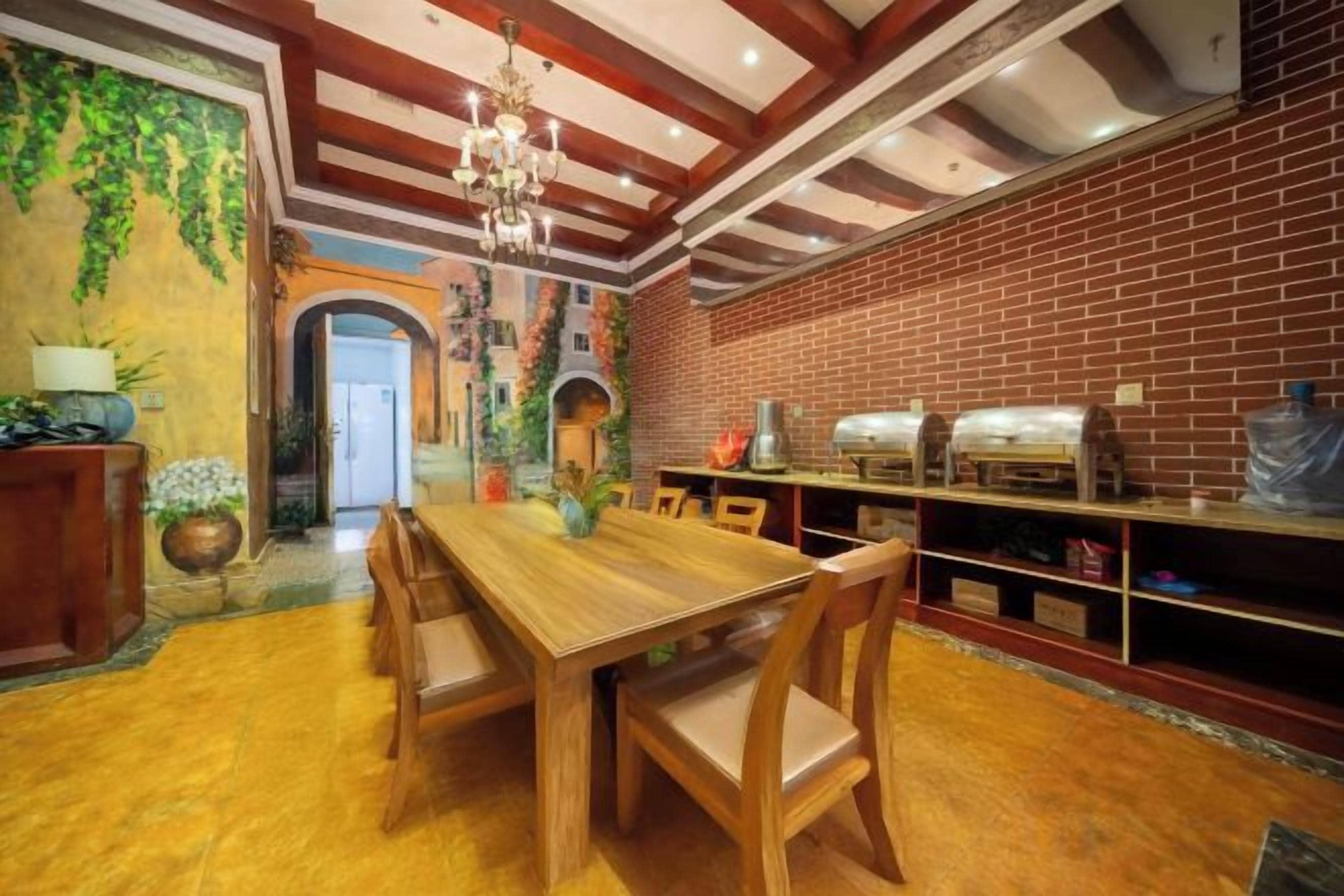A dining area with a wooden table and chairs, a brick wall, and a chandelier.