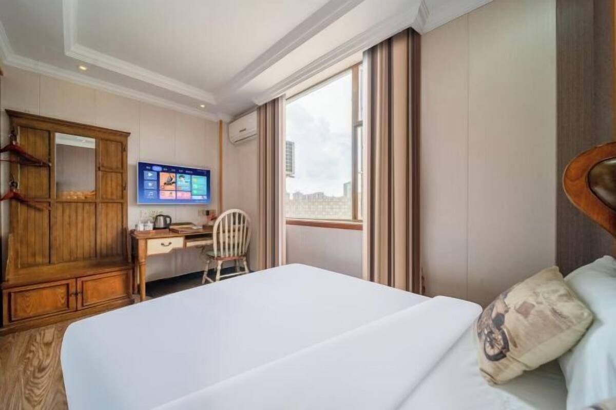 Een hotelkamer met een bed, een bureau, een stoel, een televisie en een kledingkast.