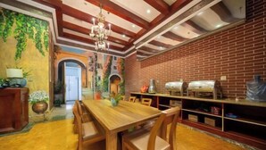 Un comedor con mesa y sillas de madera, pared de ladrillo y una araña.
