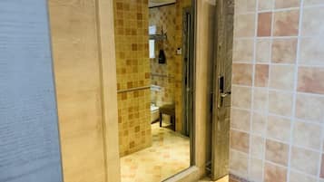 A bathroom with a glass shower enclosure, tiled walls, and a visible toilet.