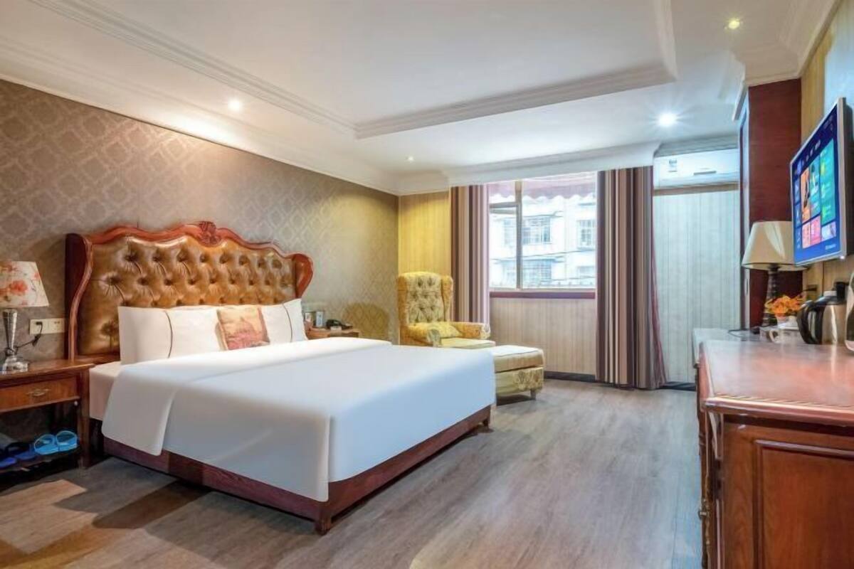 Een hotelkamer met een groot bed, een stoel, een bureau en een televisie.