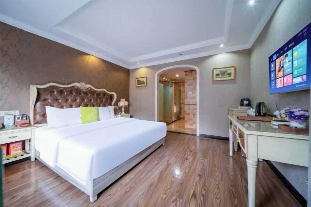 Een hotelkamer met een groot bed, een bureau en een aan de muur bevestigde televisie.