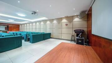 A conference room with a wooden floor, teal seating, a projector, and a screen.