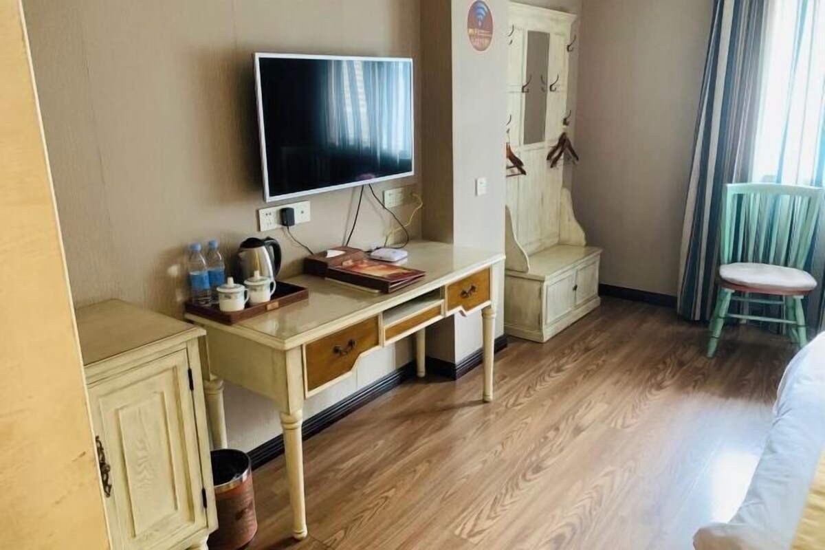 Une chambre d’hôtel avec un plancher en bois, un bureau doté d’un téléviseur à écran plat, une petite armoire et une chaise.