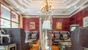 Una habitación con candelabro, asientos de cuero y obras de arte en las paredes.