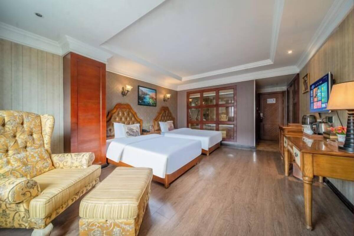 Een hotelkamer met een bank, twee bedden, een bureau en een televisie.
