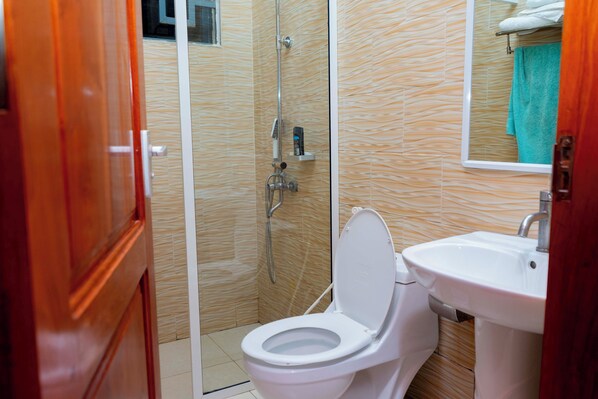 Un baño con inodoro blanco, lavamanos y ducha.